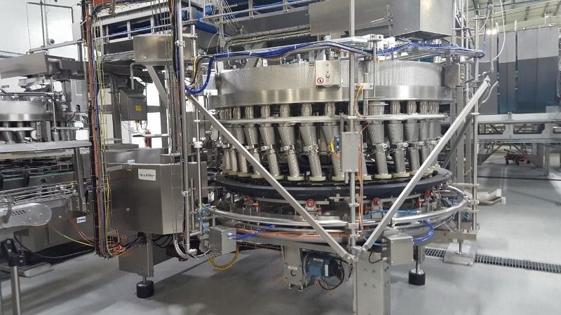Industrial rotary bottling machine with multiple filling heads.